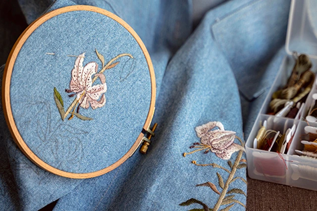 Stitched Embroidery on Denim Fabric with Needlework Supplies Nearby