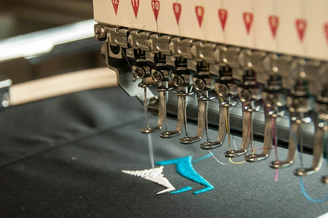 Embroidery Machine Creating Stitched Design on Black Fabric