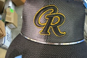 Black Hat with Yellow Stitched Embroidery Logo on a Table